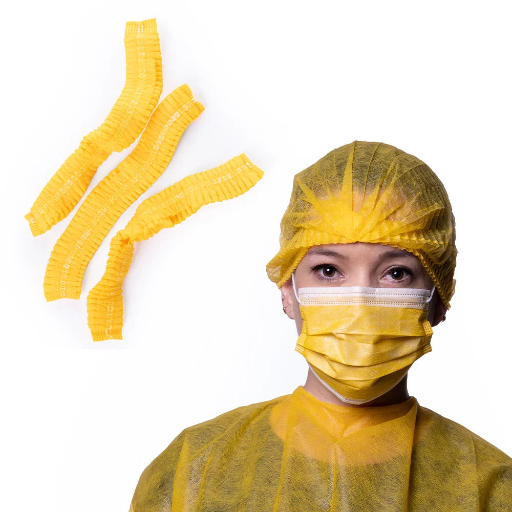 Hospital worker wearing yellow disposable gown, bouffant cap, and mask with extra caps shown
