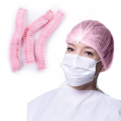 Woman wearing pink disposable bouffant cap and face mask, with extra pink bouffant caps shown. Hospital disposable supplier.