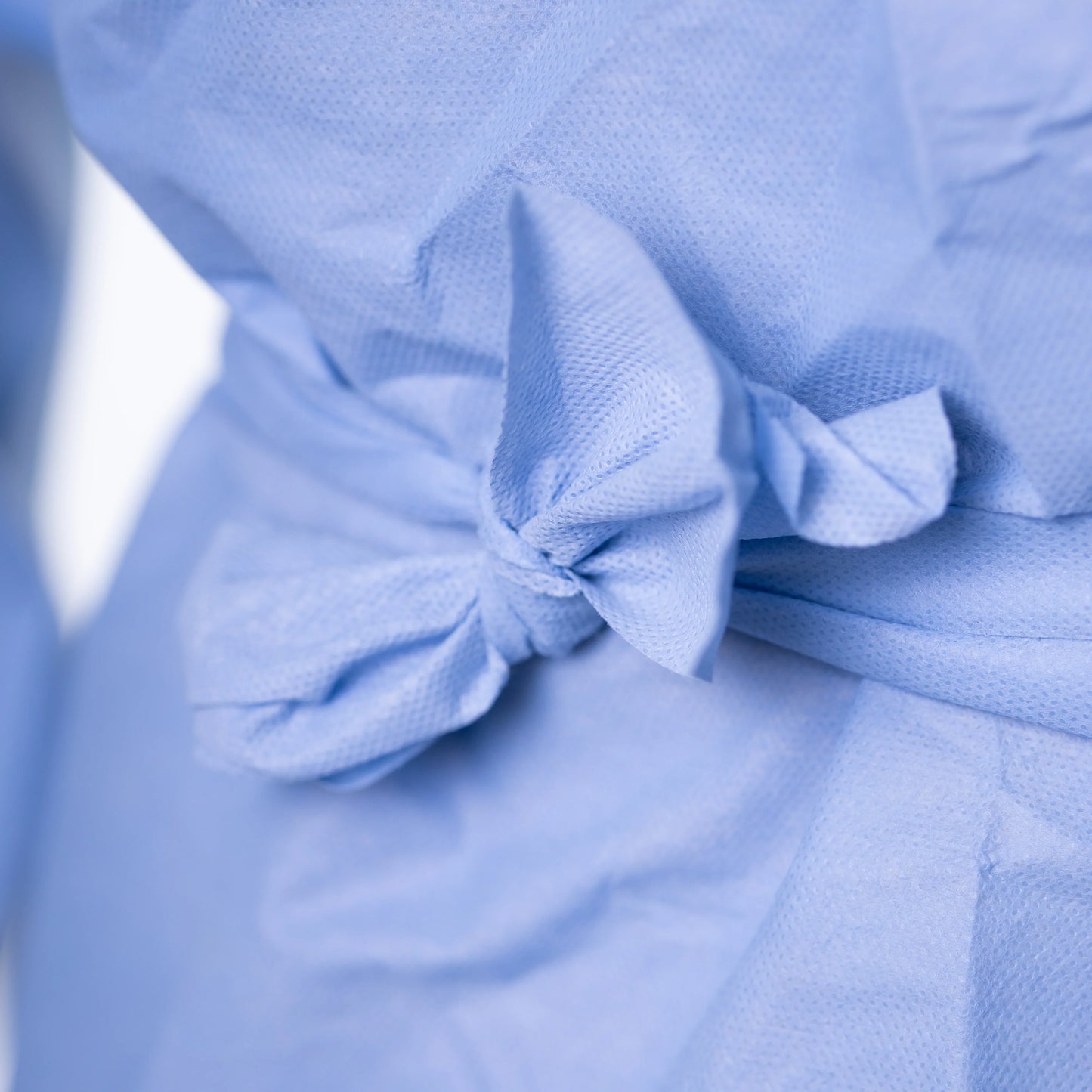 Close-up of blue disposable hospital gown tied at waist, medical gown supplier MEGA USA